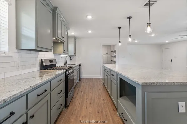 a large kitchen with stainless steel appliances granite countertop a sink a stove and a wooden floors