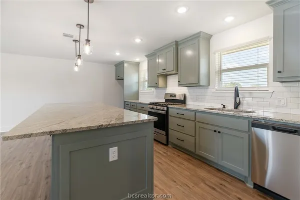 a kitchen with granite countertop a sink a counter space appliances and cabinets