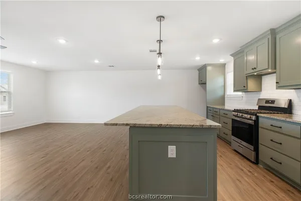 a kitchen with a stove and a wooden floor