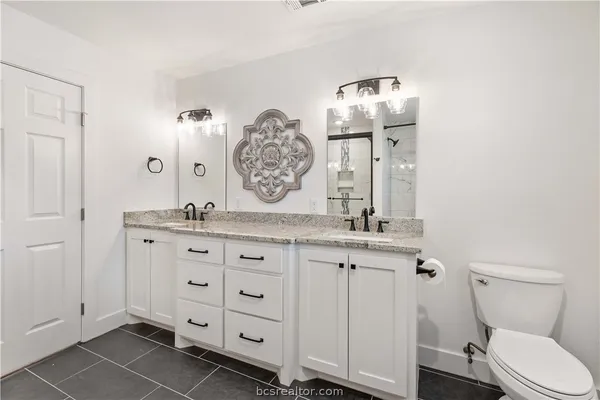 a bathroom with a granite countertop toilet sink and mirror
