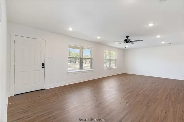 an empty room with wooden floor and windows
