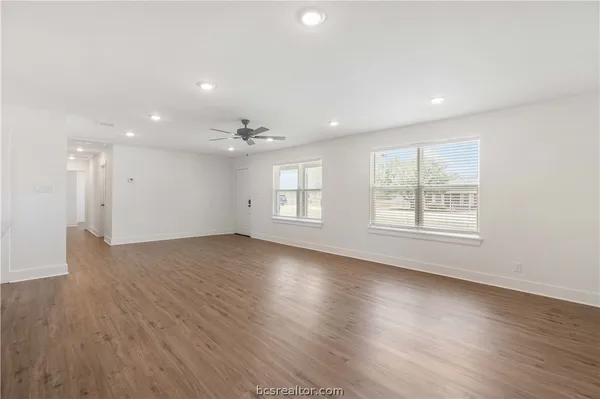 a view of an empty room with wooden floor and a window
