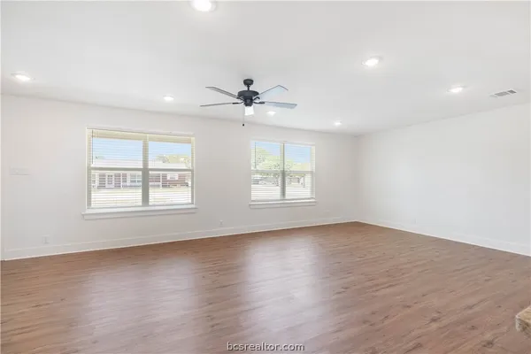an empty room with wooden floor and windows