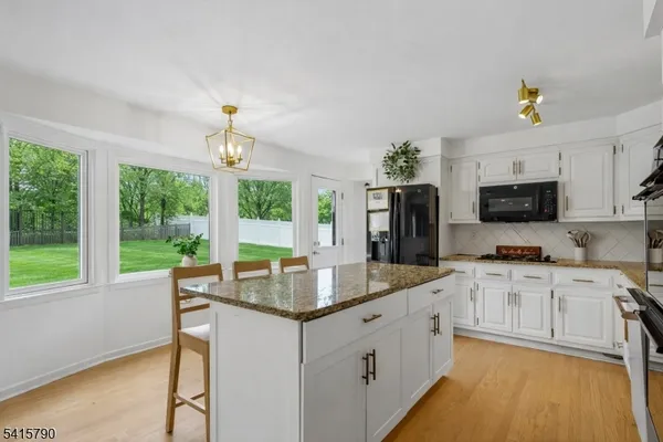 a kitchen with stainless steel appliances granite countertop a stove top oven a sink dishwasher and a refrigerator with wooden floor