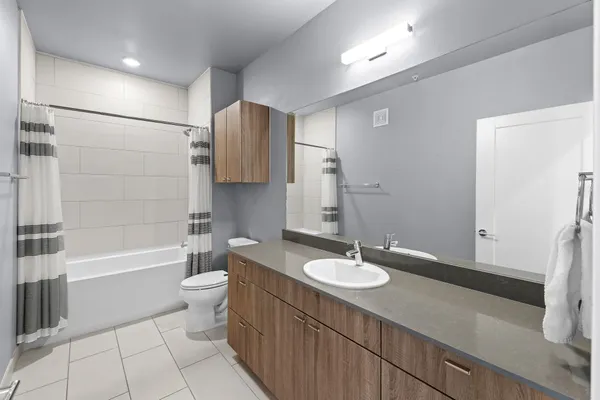 a bathroom with a sink a toilet a mirror a bathtub and shower