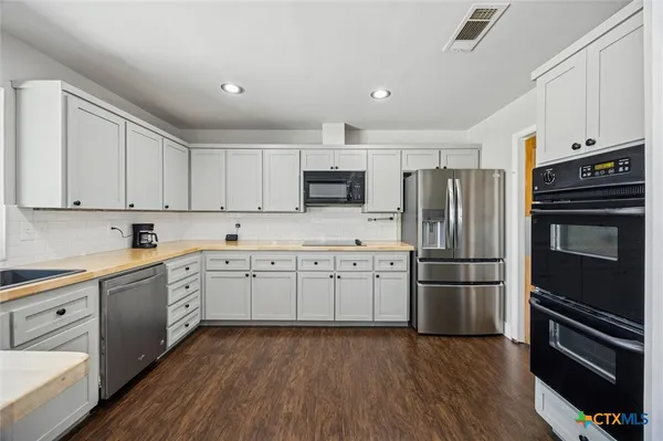 a kitchen with granite countertop appliances cabinets and a wooden floor
