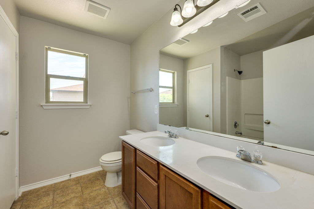 210 Cushman Drive Kyle, TX 78640 - Photo 15 of 21 Dual vanity with white undermount sinks and a spacious countertop, set atop a wood-finish cabinet