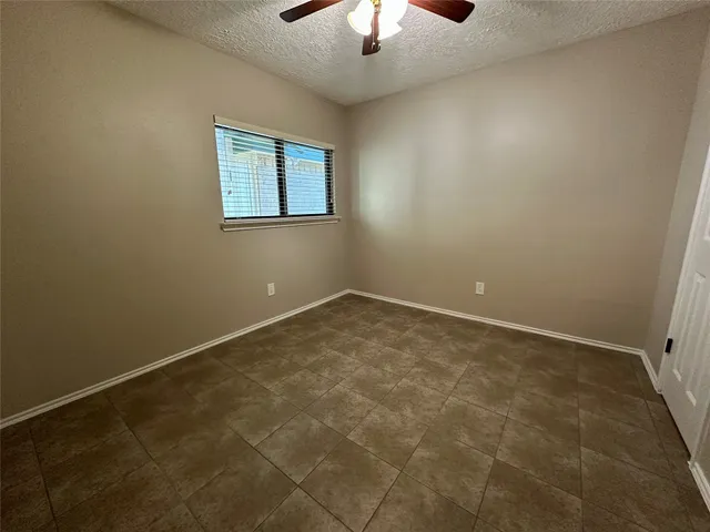 an empty room with a ceiling fan and a rug