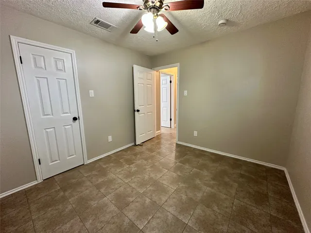 a view of an empty room with a chandelier fan