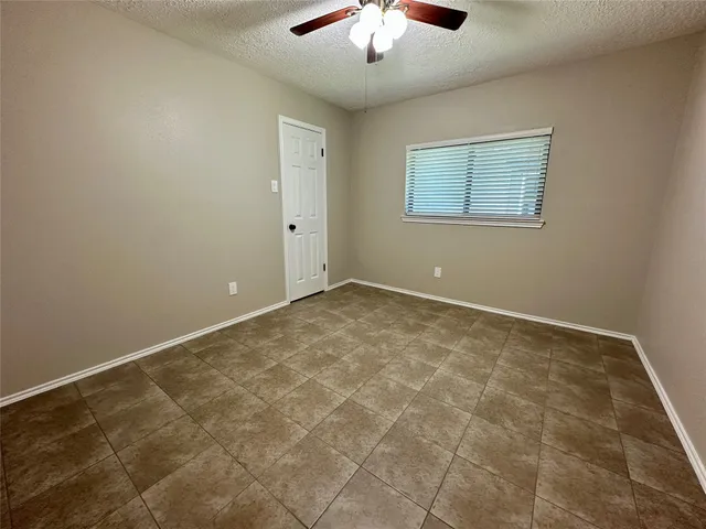an empty room with a ceiling fan and carpet