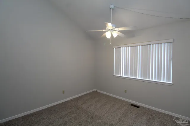 an empty room with a window and chandelier fan