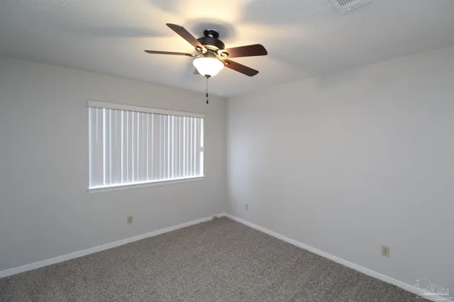 an empty room with a window and a fan
