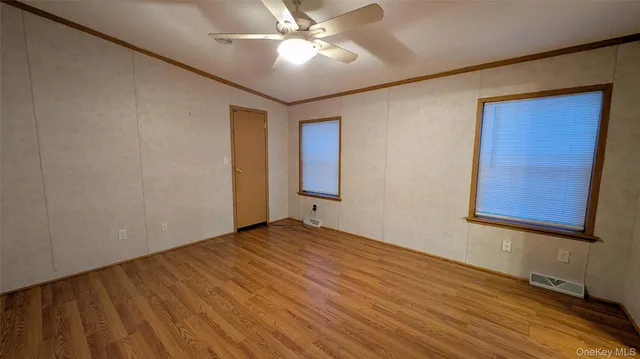 a view of an empty room with window and wooden floor