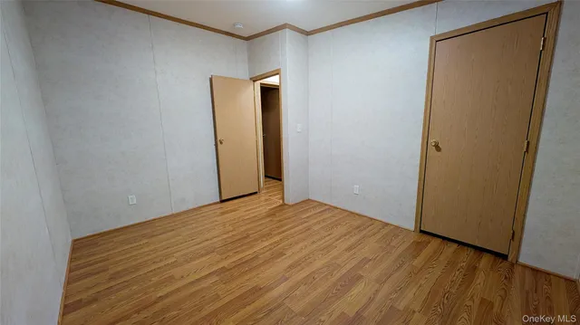 a view of an empty room with wooden floor and closet