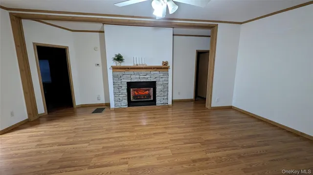 a view of an empty room with wooden floor fireplace and a window