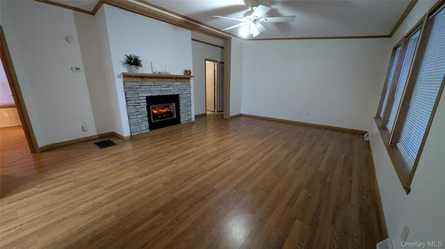 a view of an empty room with wooden floor and a fireplace