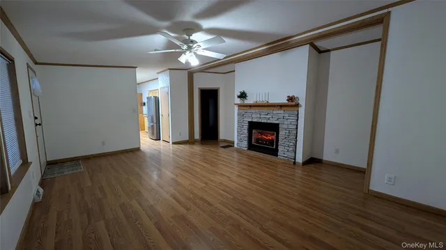 a view of an empty room with wooden floor fireplace and a window