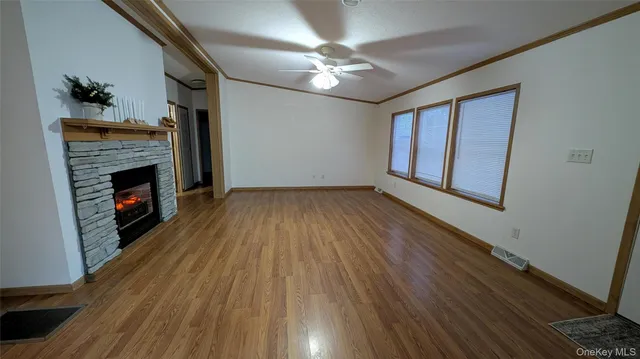 a view of an empty room with wooden floor fireplace and a window