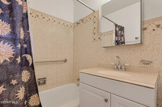 a bathroom with a granite countertop sink a mirror a shower and vanity