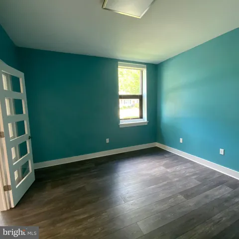 a view of an empty room with wooden floor and entryway