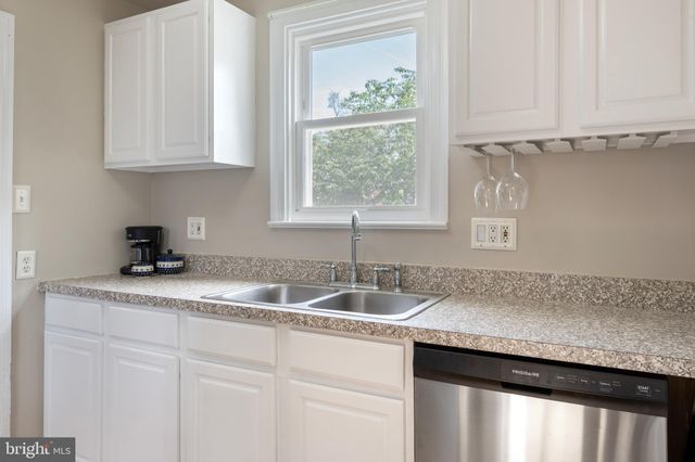 a kitchen with granite countertop a sink window and cabinets