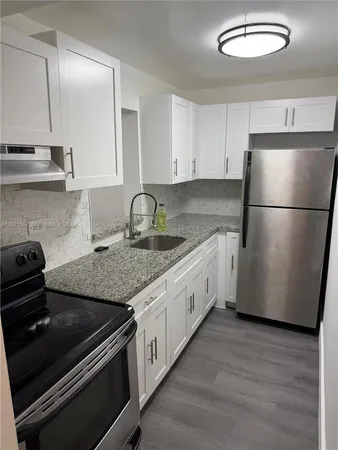 a kitchen with granite countertop a refrigerator sink and stove