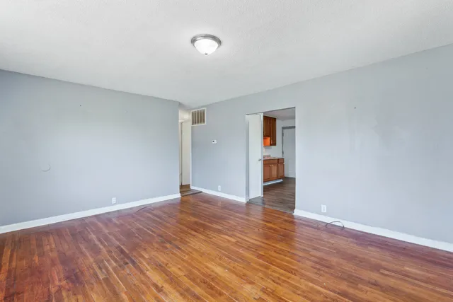 a view of an empty room with wooden floor and closet