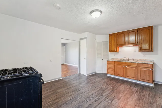 a kitchen with granite countertop a stove cabinets and wooden floor