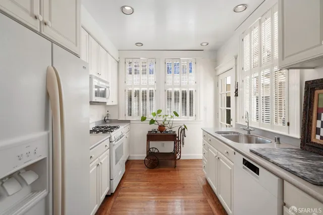 a large white kitchen with granite countertop a lot of counter space and appliances