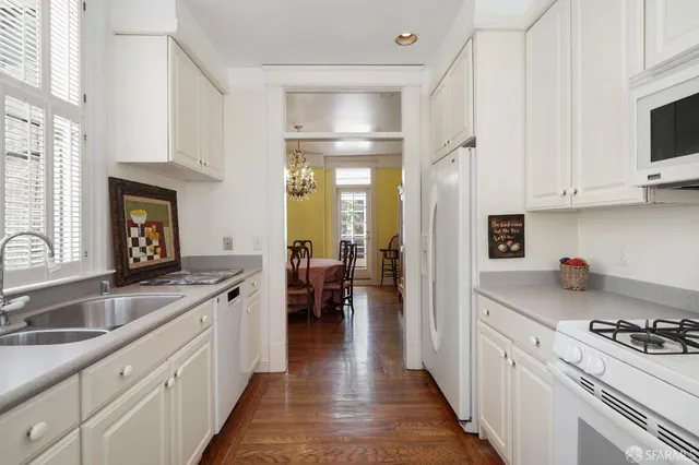 a kitchen with white cabinets and appliances