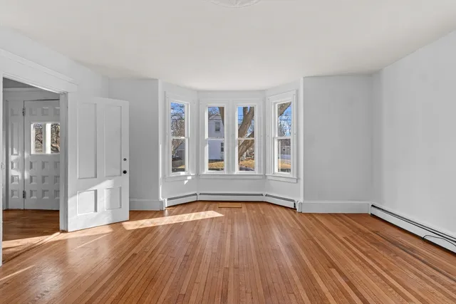 a view of an empty room with wooden floor and a window