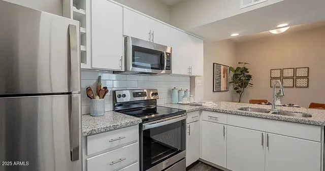 a kitchen with granite countertop a refrigerator stove and microwave