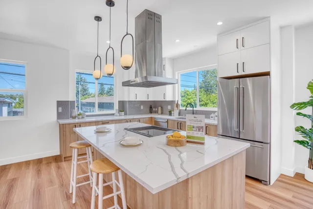 a kitchen with stainless steel appliances granite countertop a sink a refrigerator and a stove with wooden floor