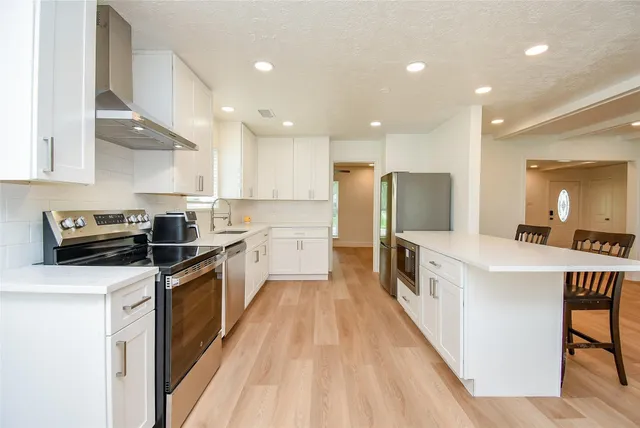a kitchen with stainless steel appliances a sink a stove top oven a counter space and cabinets