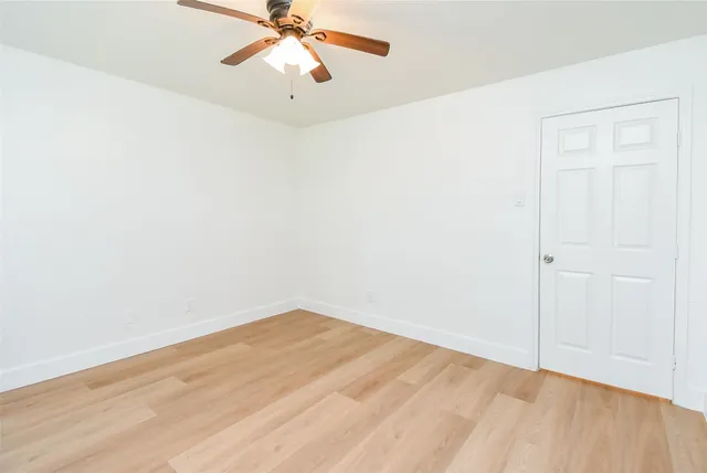 an empty room with a window and a ceiling fan