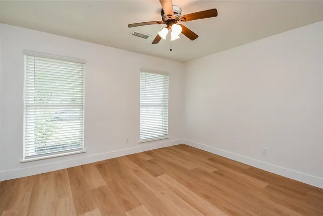 a view of empty room with wooden floor and fan
