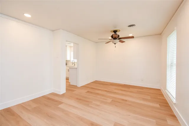 a view of empty room with wooden floor and ceiling fan