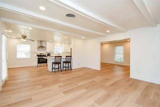 a view of an empty room and kitchen with furniture and wooden floor