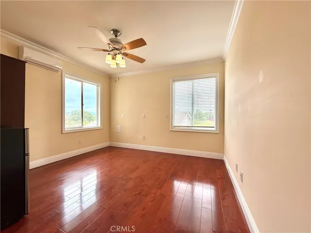a view of empty room with wooden floor and fan