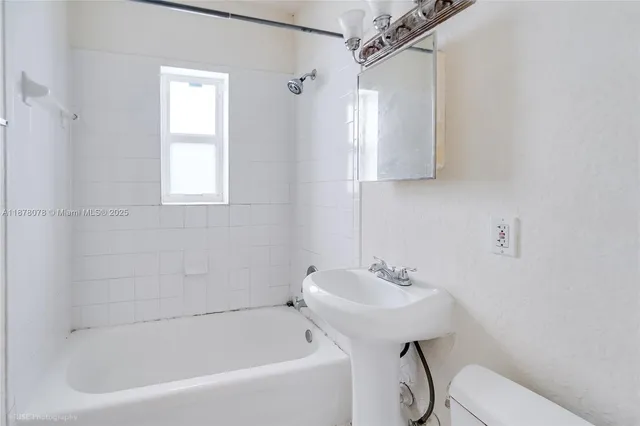a white bath tub sitting next to a white sink and a mirror