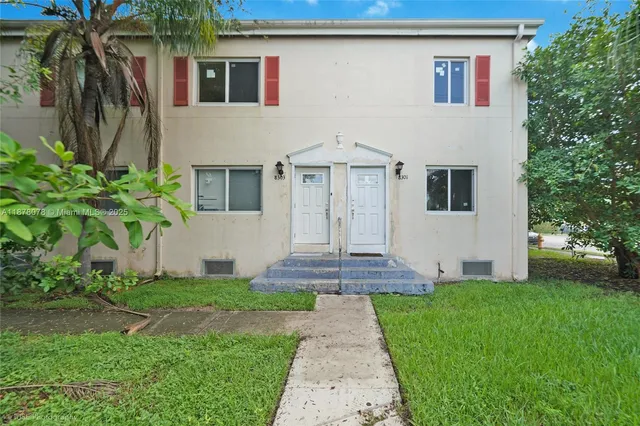a front view of a house with a yard and potted plants