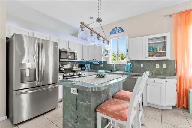 a kitchen with stainless steel appliances granite countertop a refrigerator a stove a sink a dining table and chairs