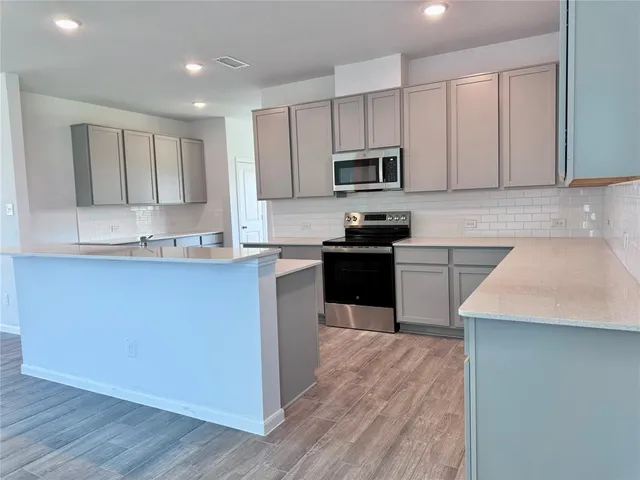 a kitchen with stainless steel appliances granite countertop a stove top oven a sink and a microwave