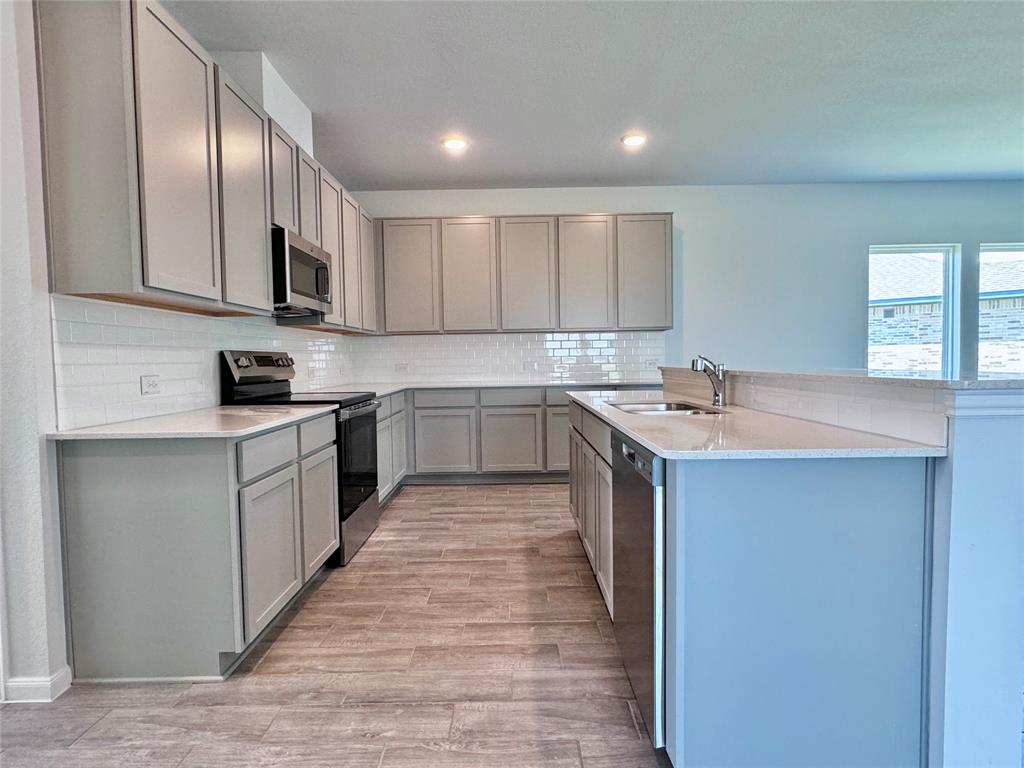 1919 Aleia Cove Sherman, TX 75092 - Photo 13 of 32 a kitchen with stainless steel appliances granite countertop a sink a stove a refrigerator and cabinets