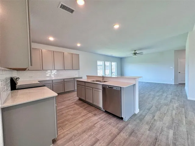 a large kitchen with a lot of counter space and wooden floor