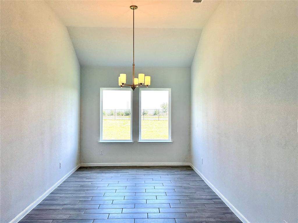 1919 Aleia Cove Sherman, TX 75092 - Photo 5 of 32 a view of an empty room with wooden floor chandeliers and a window
