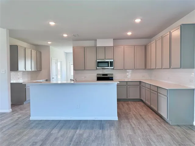 a large kitchen with cabinets wooden floor and stainless steel appliances