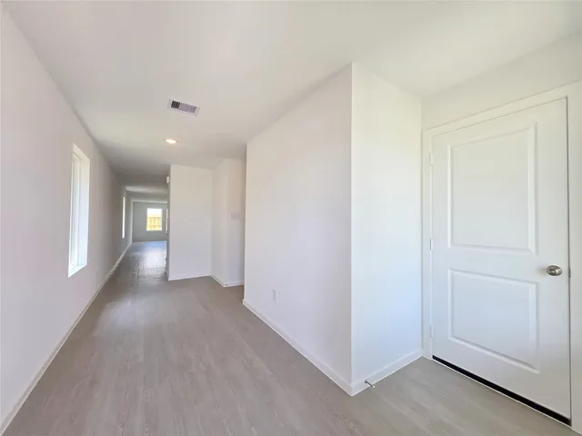 a view of a hallway with wooden floor and windows