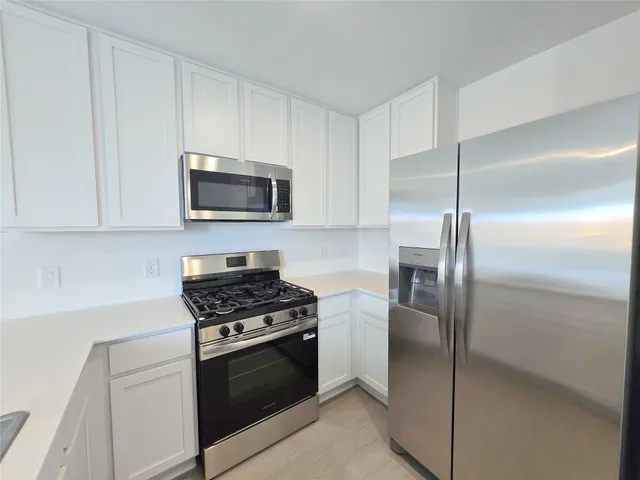 a kitchen with stainless steel appliances granite countertop a refrigerator stove and microwave