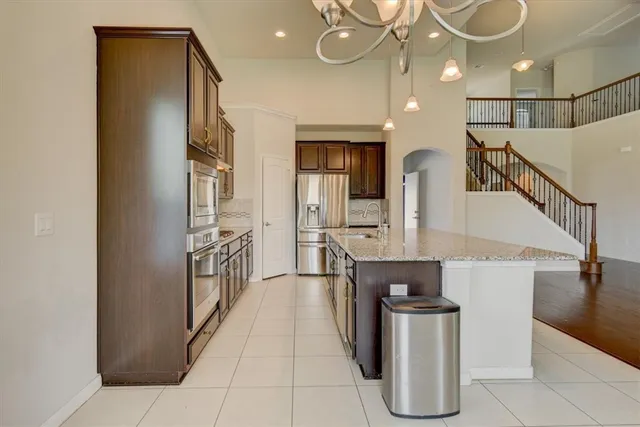a kitchen with stainless steel appliances kitchen island granite countertop a refrigerator a stove and a sink